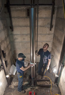 Two Delta technicians preparing to replace a hydraulic elevator cylinder