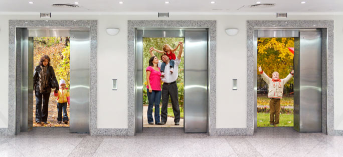 A marble lobby with 3 elevators, elevator doors are covered with large pictures of a family in an autumn forest